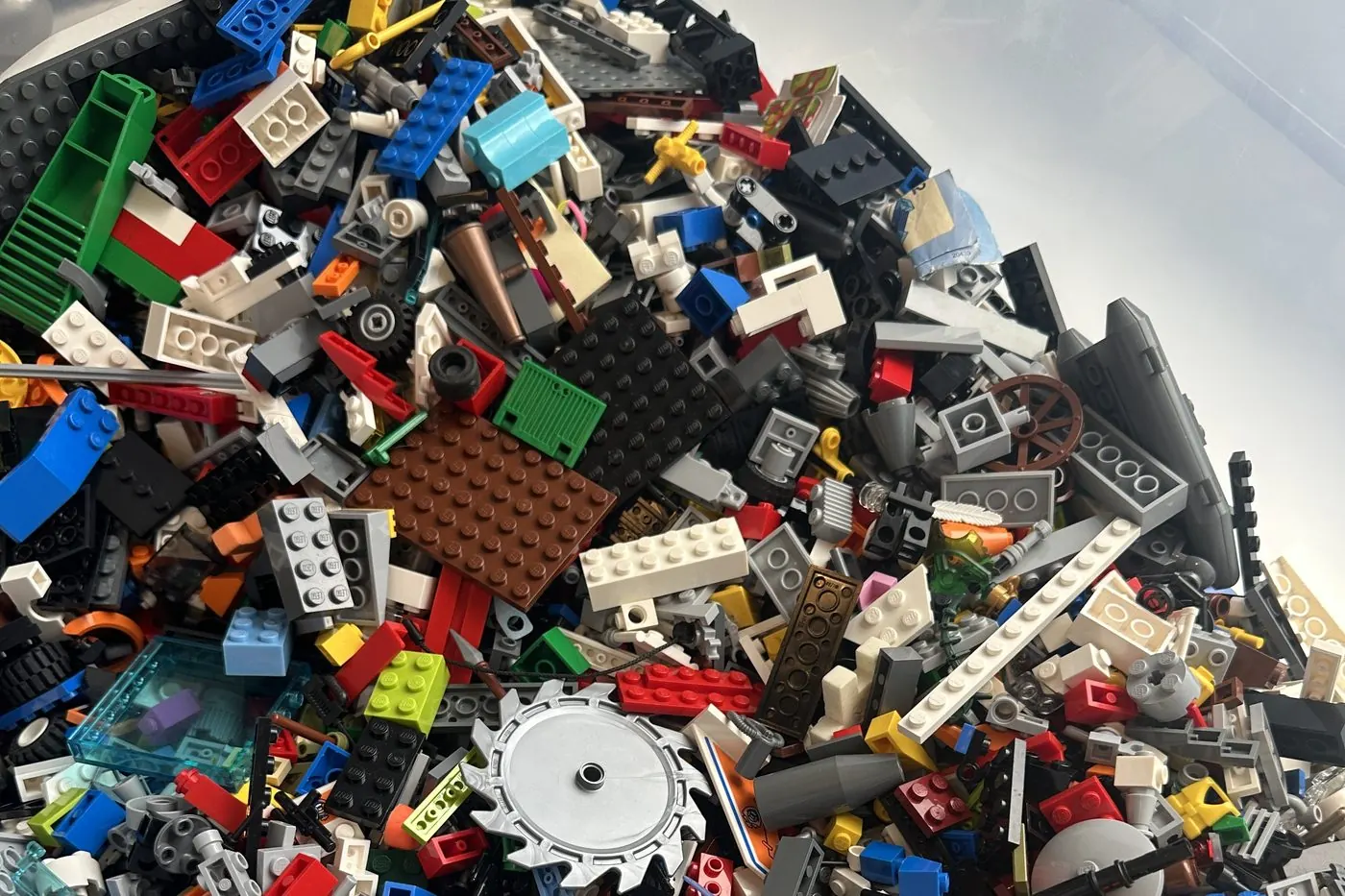 A tub of mixed LEGO bricks containing many light and dark grey parts alongside brighter colours.